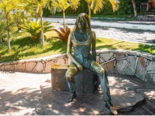 Suites Marisol Buzios في بوزيوس: تمثال لامرأة جالسة على مقاعد