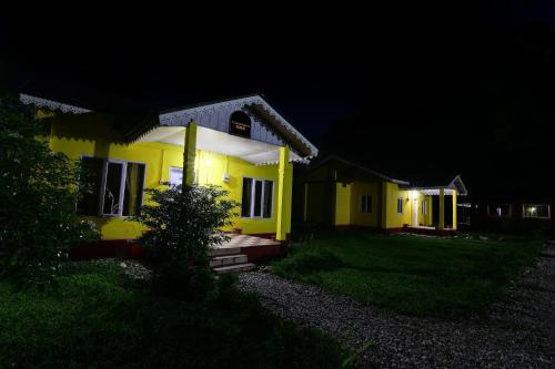 a yellow house at night with the lights on at Townhouse OAK Gorumara Jungle Resort in Chālsa Mahābāri