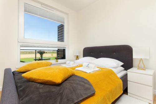 a bedroom with two beds with yellow sheets and a window at Apartment in Northern Gdynia by Renters in Gdynia
