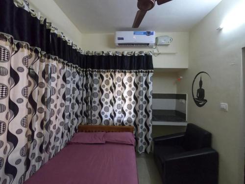 a room with a bed and curtains and a chair at Kripa Residency in Cochin