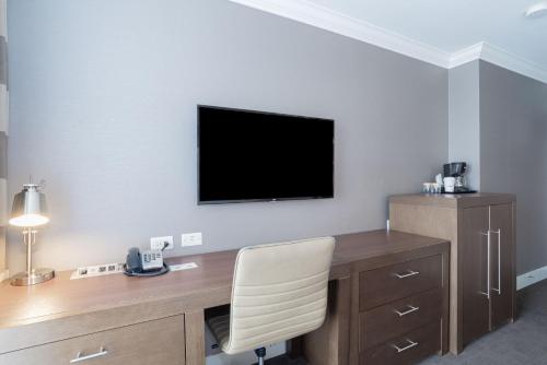 a room with a desk with a television on a wall at Sandman Hotel Edmonton West in Edmonton