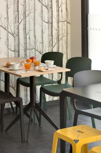 a table and chairs in a room with trees on the wall at Ténéo Apparthôtel Bordeaux Maritime - Cité du vin in Bordeaux
