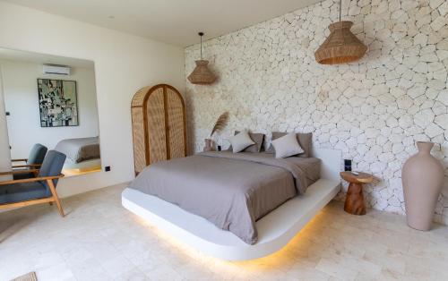 a bedroom with a large bed and a chair at Karma House Ungasan in Jimbaran