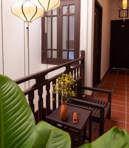 a balcony with a table and a vase of flowers at Hoianese Heritage Hotel - Truly Hoi An in Hoi An