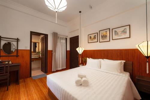 a bedroom with a white bed with two towels on it at Hoianese Heritage Hotel - Truly Hoi An in Hoi An