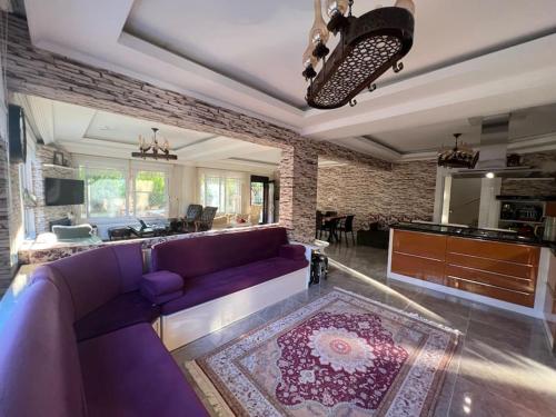 a living room with a purple couch and a kitchen at Çamlarkent Villaları 