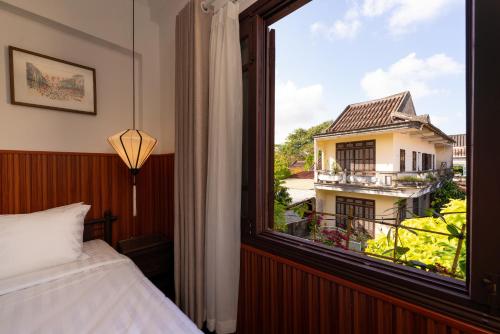 um quarto com uma janela com vista para um edifício em Hoianese Heritage Hotel - Truly Hoi An em Hoi An
