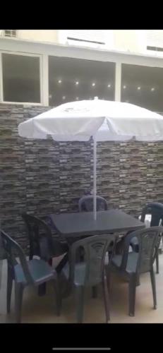 a table and chairs with a white umbrella at Residence kettani Bouznika in Bouznika