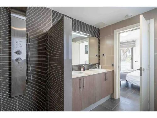 ein Bad mit einem Waschbecken, einem Spiegel und einem Bett in der Unterkunft Villa Golf and Pool Oasis in Catllar