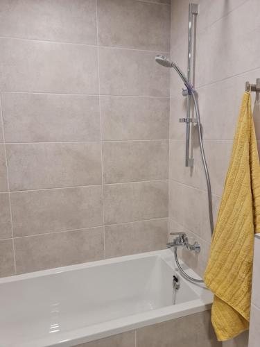 a bathroom with a tub and a shower with a yellow towel at Studio apartamentas su balkonu in Vilnius