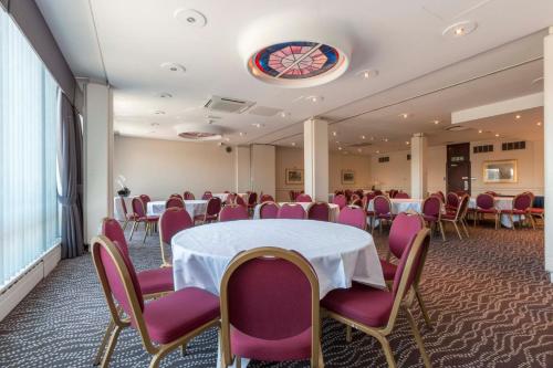 a conference room with a white table and purple chairs at Thistle London Heathrow Terminal 5 in Hillingdon