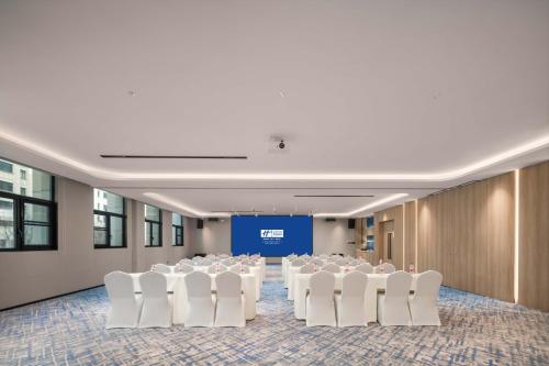 a conference room with white chairs and a screen at Holiday Inn Express Shanghai Hongqiao NECC by IHG in Shanghai