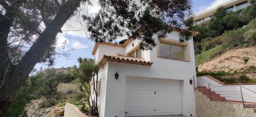 a white house with a garage on a hill at Villa Mas Nou in Castillo de Aro