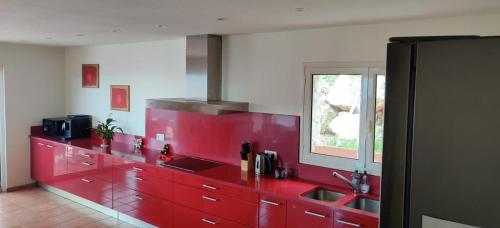 eine Küche mit roten Schränken und einem Fenster in der Unterkunft Villa Mas Nou in Castillo de Aro