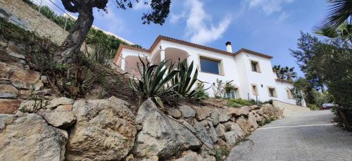 a white house behind a stone wall at Villa Mas Nou in Castillo de Aro