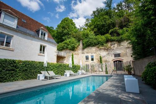 a swimming pool with lounge chairs next to a house at Domaine La Restrie - La Grande Salle des Médicis in Pocé-sur-Cisse