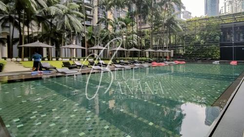 einen Pool mit Stühlen und Sonnenschirmen in einem Gebäude in der Unterkunft St Mary Luxury Signature Suites, KLCC by BlueBanana in Kuala Lumpur