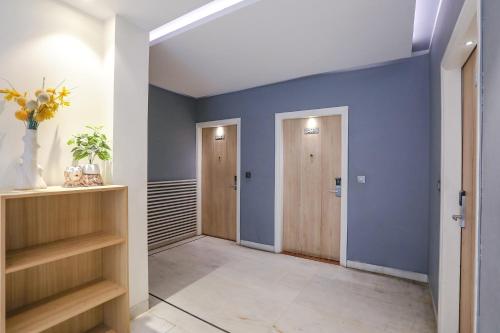 a hallway with blue walls and wooden shelves at FabHotel JHS Studio in Gurgaon