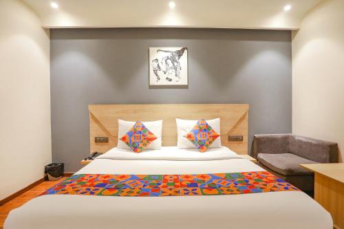 a bedroom with a large bed and a chair at FabHotel JHS Studio in Gurgaon