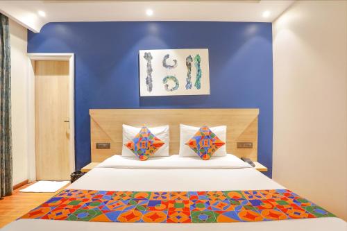 a bedroom with a large bed with a blue wall at FabHotel JHS Studio in Gurgaon