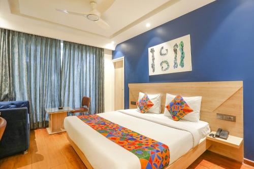 a hotel room with a bed and a blue wall at FabHotel JHS Studio in Gurgaon