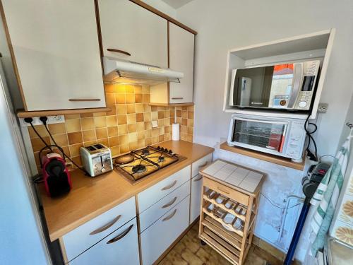 une petite cuisine avec des armoires blanches et un micro-ondes dans l'établissement Kent studio by Welcome to Cannes, à Cannes