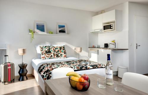 a room with a bed and a table with a bowl of fruit at Ténéo Apparthôtel Bordeaux Maritime - Cité du vin in Bordeaux