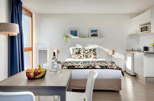 a bedroom with a bed and a table with a bowl of fruit at Ténéo Apparthôtel Bordeaux Maritime - Cité du vin in Bordeaux