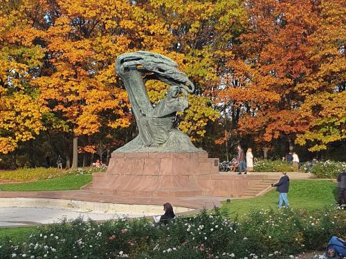 een standbeeld in een park met mensen die er omheen lopen bij Royal Łazienki Park by Better Place in Warschau