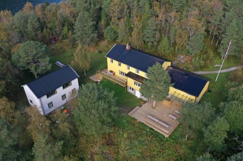 una vista aérea de una gran casa amarilla con techo negro en Unique totally private island in a Norwegian fjord with space for 40 people, a dinner room and a chapel, en Simle