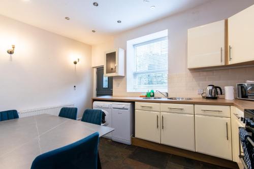 a kitchen with white cabinets and a table and chairs at Lovely 2-Bedroom Conveniently Close to Bury & Manchester in Stubbins