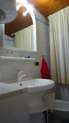uma casa de banho branca com um lavatório e um espelho em campiglio; dedica a te la calda mansarda di pia em Madonna di Campiglio