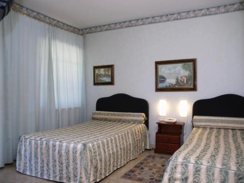 a bedroom with two beds and a table with two lamps at HOTEL IL SILLABARIO in Iglesias