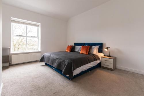 a white bedroom with a bed and a window at Lovely 2-Bedroom Conveniently Close to Bury & Manchester in Stubbins