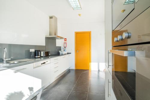 une cuisine avec des placards blancs et une porte jaune dans l'établissement Villas Novochoro - Small Garden, à Albufeira