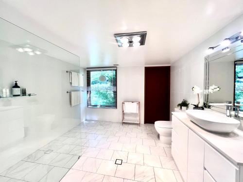 Baño blanco con lavabo y aseo en French Provincial The Garden Suite at Chapmans incl Breakfast & Golf en Moss Vale