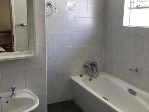 Baño blanco con bañera y lavamanos en 40 on Ilkey B&B, en Pretoria