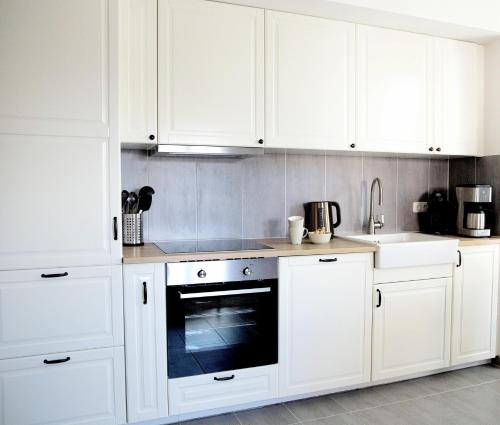 a white kitchen with white cabinets and an oven at Ferienwohnung Lasse in Glücksburg
