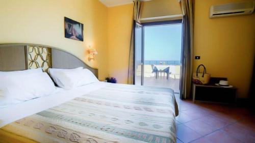 - une chambre avec un grand lit et une vue sur l'océan dans l'établissement Villaggio Porto Rhoca, à Squillace