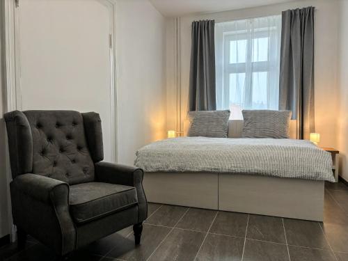 a bedroom with a bed and a chair and a window at Apartmány Plzeň Rolnické náměstí 8 in Plzeň