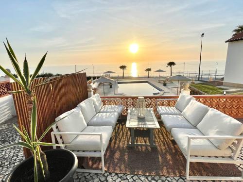 a rooftop patio with white couches and a pool at The Ocean / Ericeirahills in Carvoeira