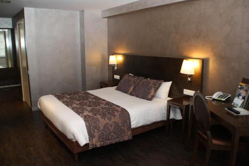 a hotel room with a bed and a desk with a telephone at Hotel De Guise Nancy Vieille Ville in Nancy