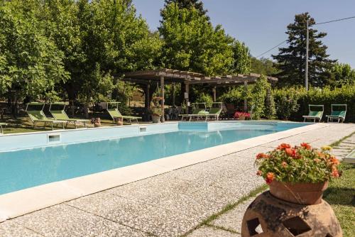 una piscina con cenador y flores en un patio en AGRITURISMO B&B BIO LA TANA DEL LELE en Serra San Quirico