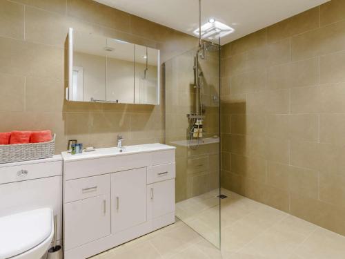 La salle de bains est pourvue d'un lavabo blanc et d'une douche. dans l'établissement 3 Bed in Porthcawl 85193, à Newton