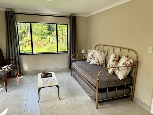 a living room with a bed and a table at The Aloe Garden Cottage in Howick