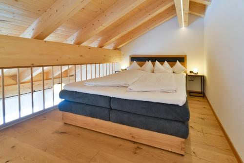 a bedroom with a bed in a loft with wooden ceilings at Haus Margrith Alpenblick Appartements in Damuls