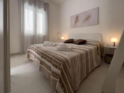 a white bedroom with a large bed with a blanket at La Corte di Greta in Favignana