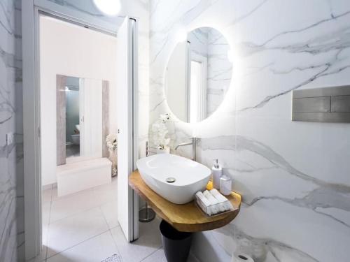 a white bathroom with a sink and a mirror at La Corte di Greta in Favignana