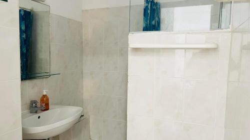 une salle de bain blanche avec un lavabo et un miroir dans l'établissement Studio PORTO 39 Lumio, à Lumio