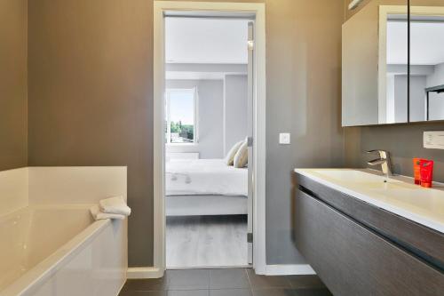 a bathroom with a tub and a sink and a bed at Het Zwinhuis - Spacious and comfortable family home near 't Zwin in Knokke-Heist